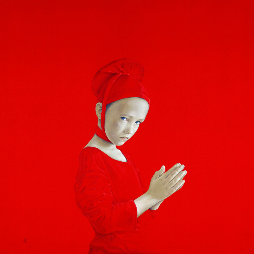 Un retrato de un niño con las manos juntas. El niño viste un atuendo y un gorro de color rojo intenso y el fondo es de un rojo brillante.